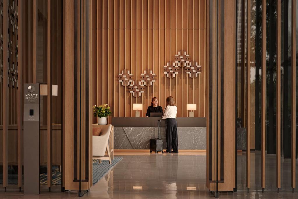 A reception counter set against a tall timber wall in the hotel entrance hall.
