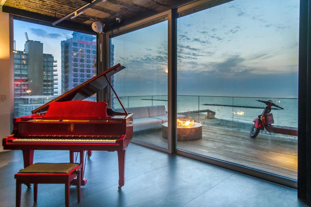 a piano in a room with a view of the ocean at Hayarkon Apartment By the Sea in Tel Aviv
