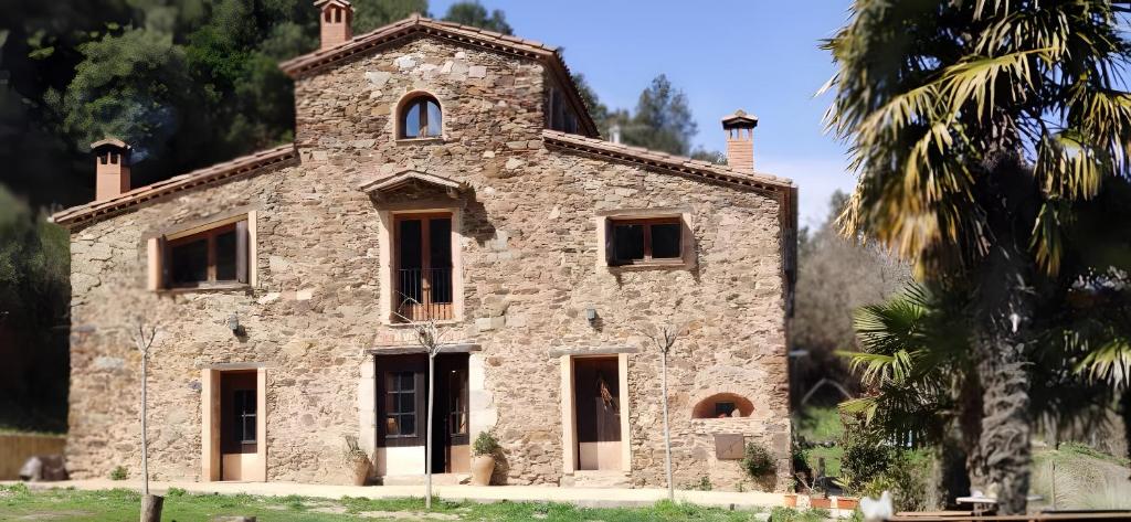 un edificio de piedra con una torre encima en Masia Sa Calma - La Tribu, en San Martín Sacalm