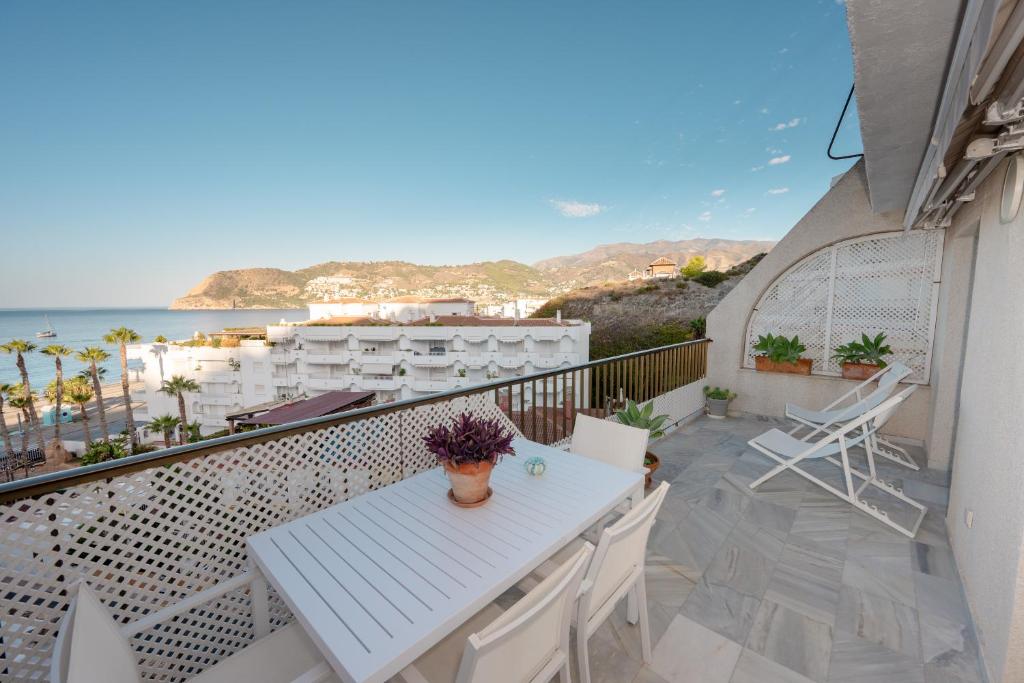 Un balcón con mesa y sillas y el mar. en Rincón de la Caleta, en La Herradura