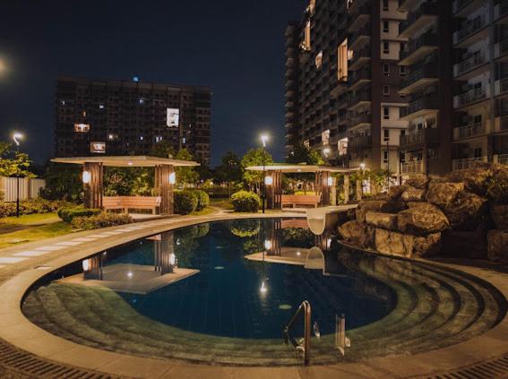 - une grande piscine en ville la nuit dans l'établissement Zen-Inspired 2 Bedroom Condo Satori Residences, à Manille