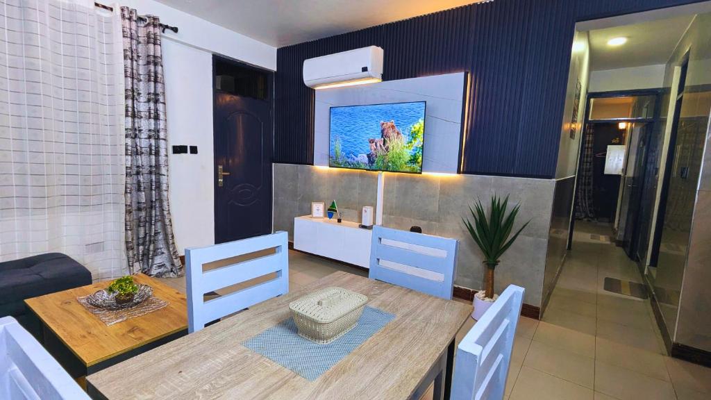 a dining room with a table and a tv on the wall at Family Home by Havana Properties with WIFI & Free Parking near Sawa Sawa Bay Beach Restaurant in Dar es Salaam