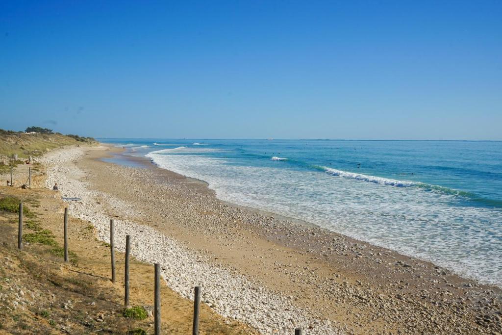 a beach with a fence next to the ocean at Villa Rétaise face mer - Sainte-Marie-de-Ré in Sainte-Marie-de-Ré