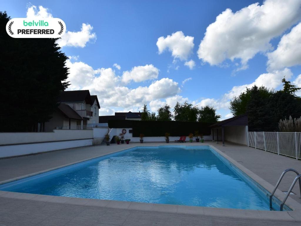 a swimming pool in a yard with clouds in the sky at Charming holiday home with pool and pond in Faverolles