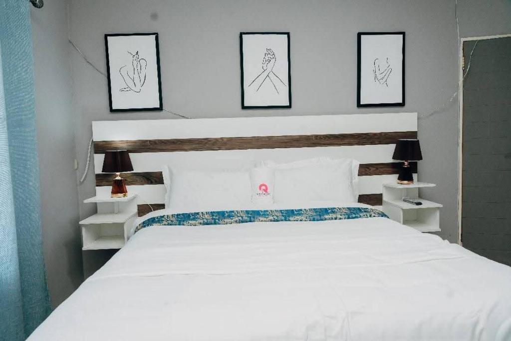 una camera da letto con un letto bianco con tre immagini sul muro di One Apartment a Gaborone
