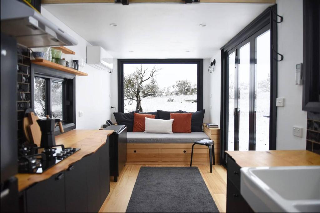 a kitchen and living room with a couch and a window at Serene Mountain Retreat in Jindabyne - Private Tiny Home in Jindabyne