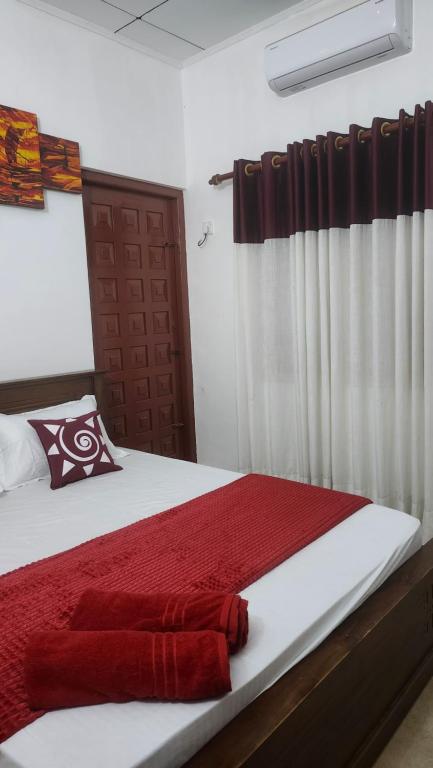 a bedroom with a bed with a red blanket at Sapphire Homestay in Dehiwala