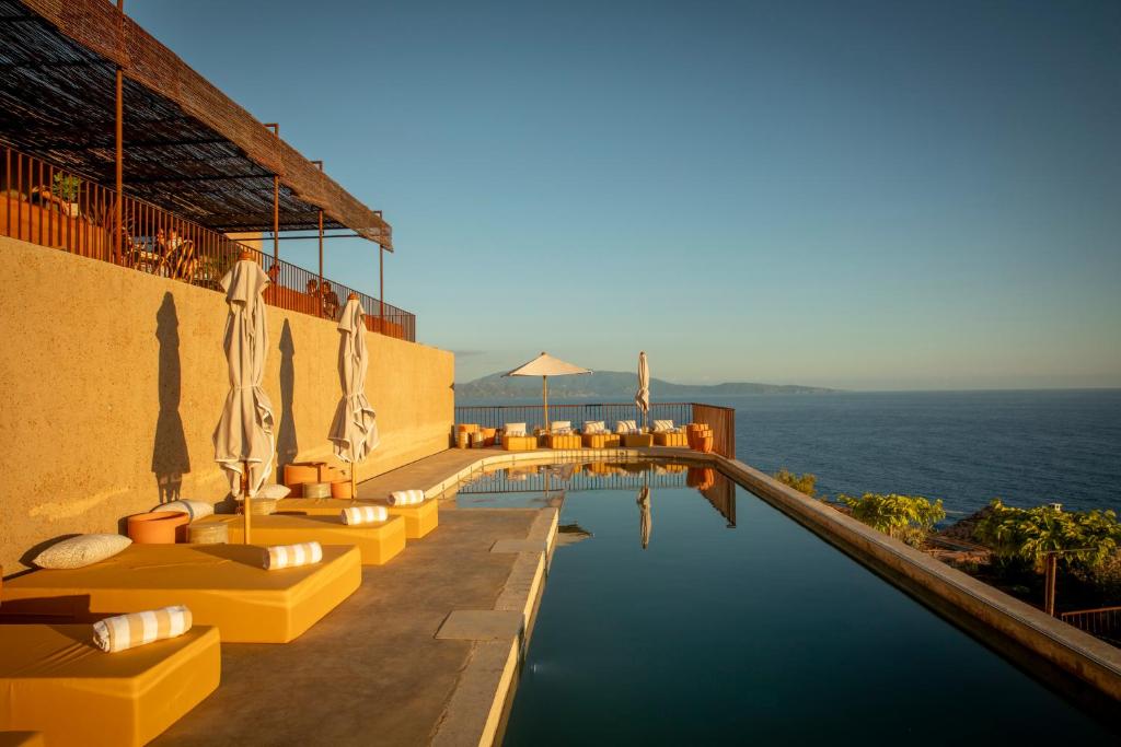 a hotel with a pool with the ocean in the background at Hôtel Mylos - Cargèse, Piscine Intérieure et Extérieure in Cargèse