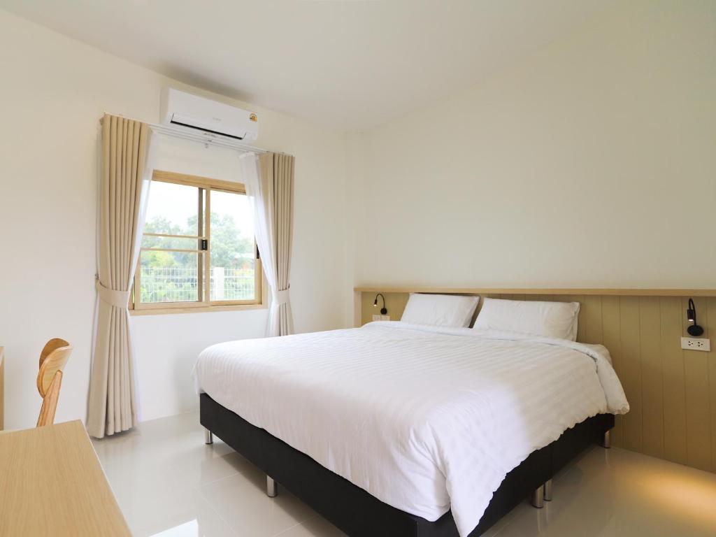een slaapkamer met een groot wit bed en een raam bij เดอะริม รีสอร์ท The Rim Resort in Ban Muang