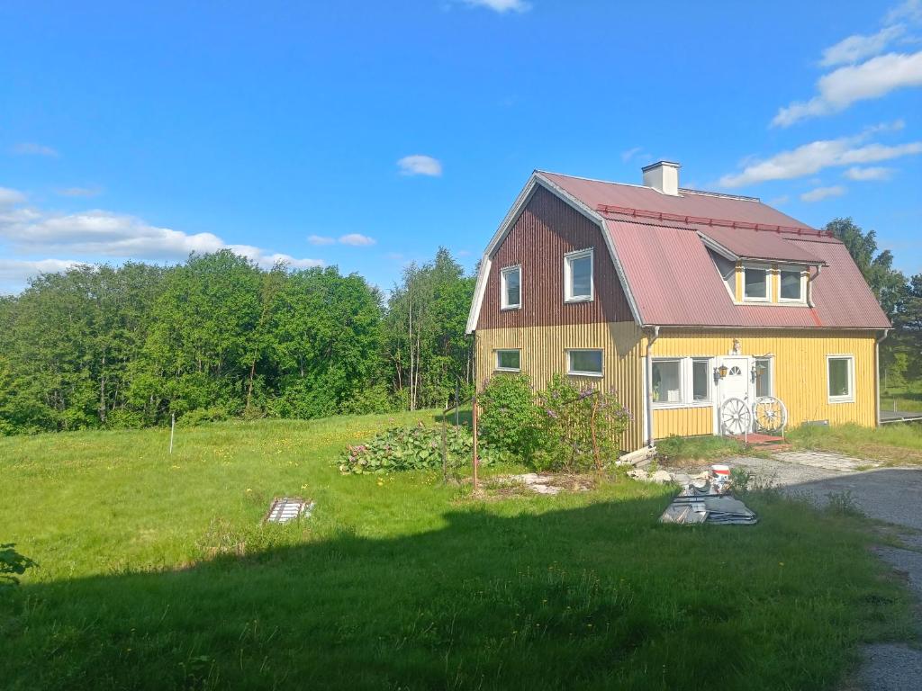 une maison avec un toit rouge sur un champ vert dans l'établissement Villa by Ångermanälven in High Coast, à Kramfors