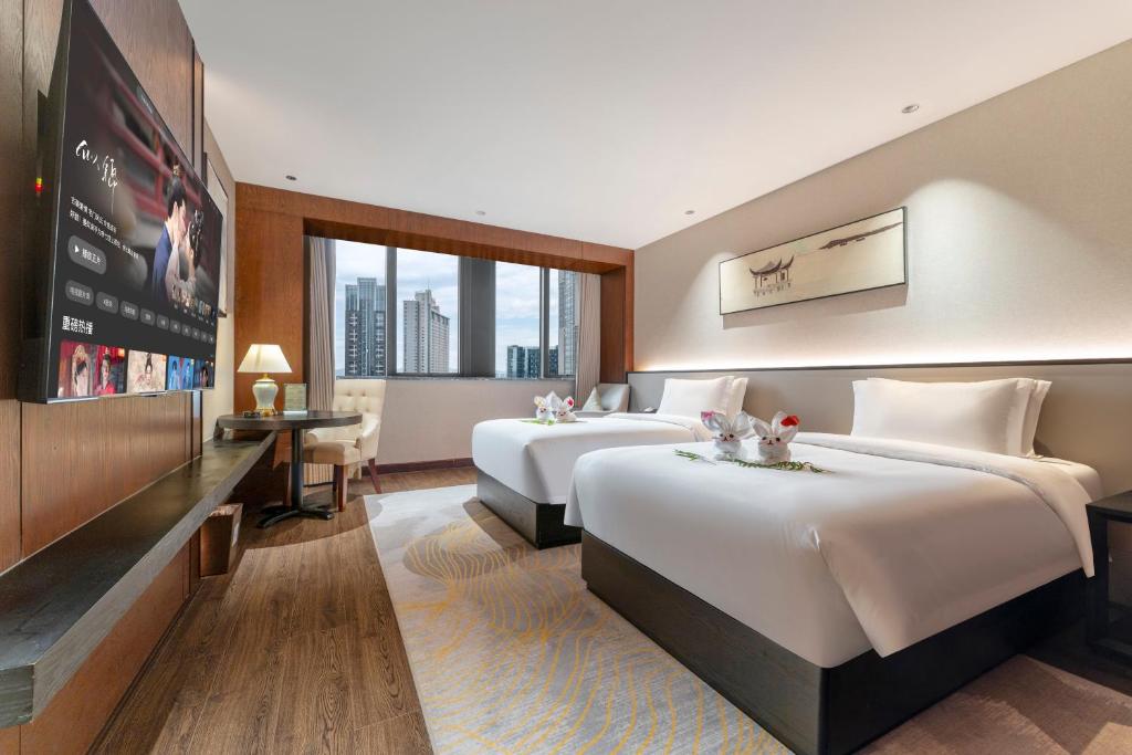 a hotel room with two beds and a tv at Chongqing Meichen Hotel Auto Expo Branch in Chongqing