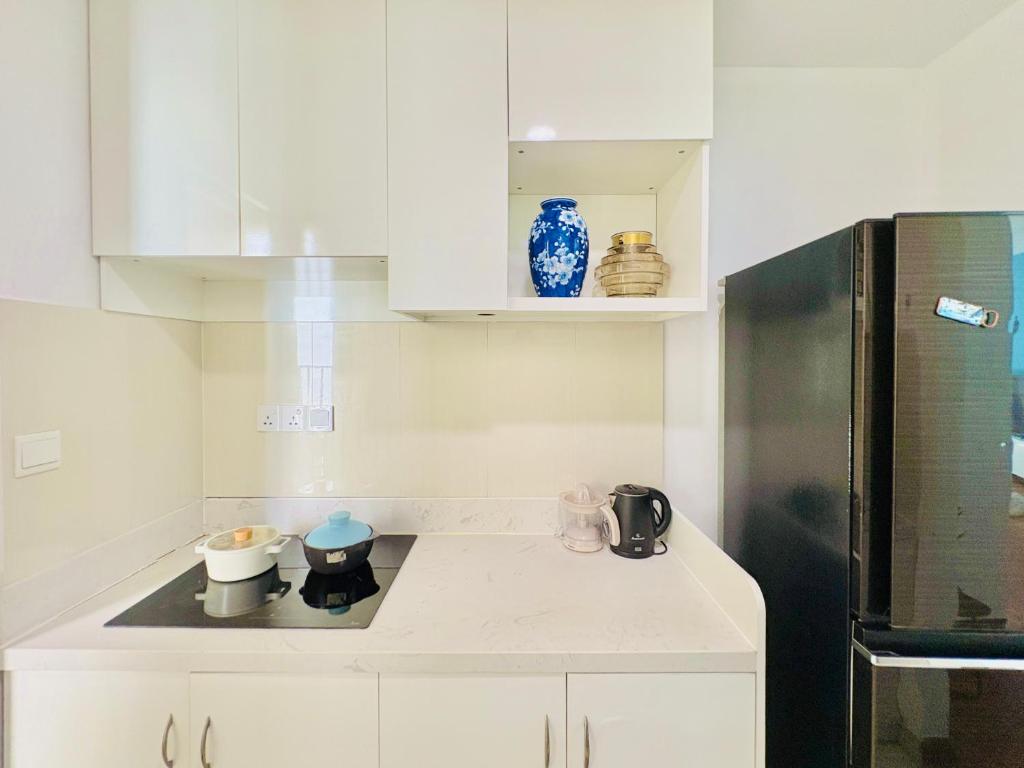 a kitchen with white cabinets and a black refrigerator at TPHomes Vista Verde in Ho Chi Minh City