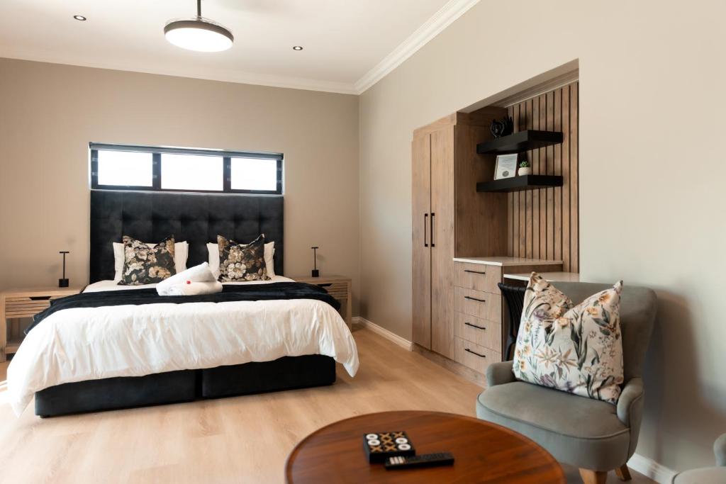 a bedroom with a bed and a chair and a table at Walton Cottages of Mill Park, Port Elizabeth in Port Elizabeth