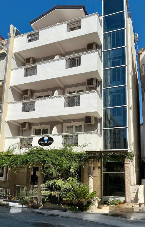 a tall white building with plants in front of it at Budva Perla di Mare Hotel in Budva