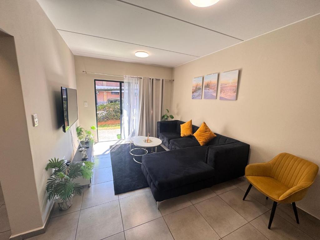 a living room with a black couch and a table at Waterfall Bay in Midrand