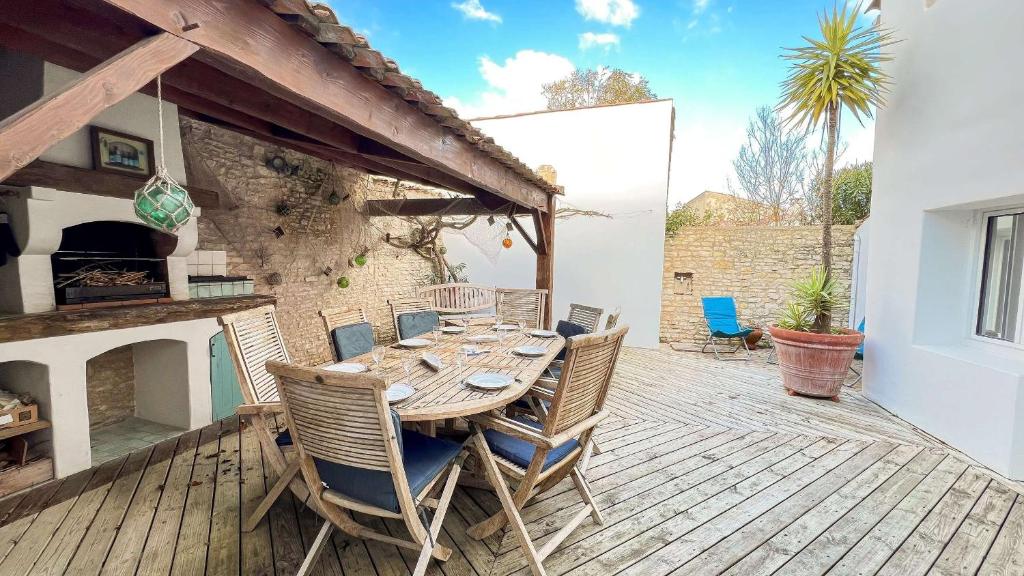 un tavolo e sedie in legno su una terrazza di legno di Charmante villa au centre de la Couarde avec cour a La Couarde-sur-Mer