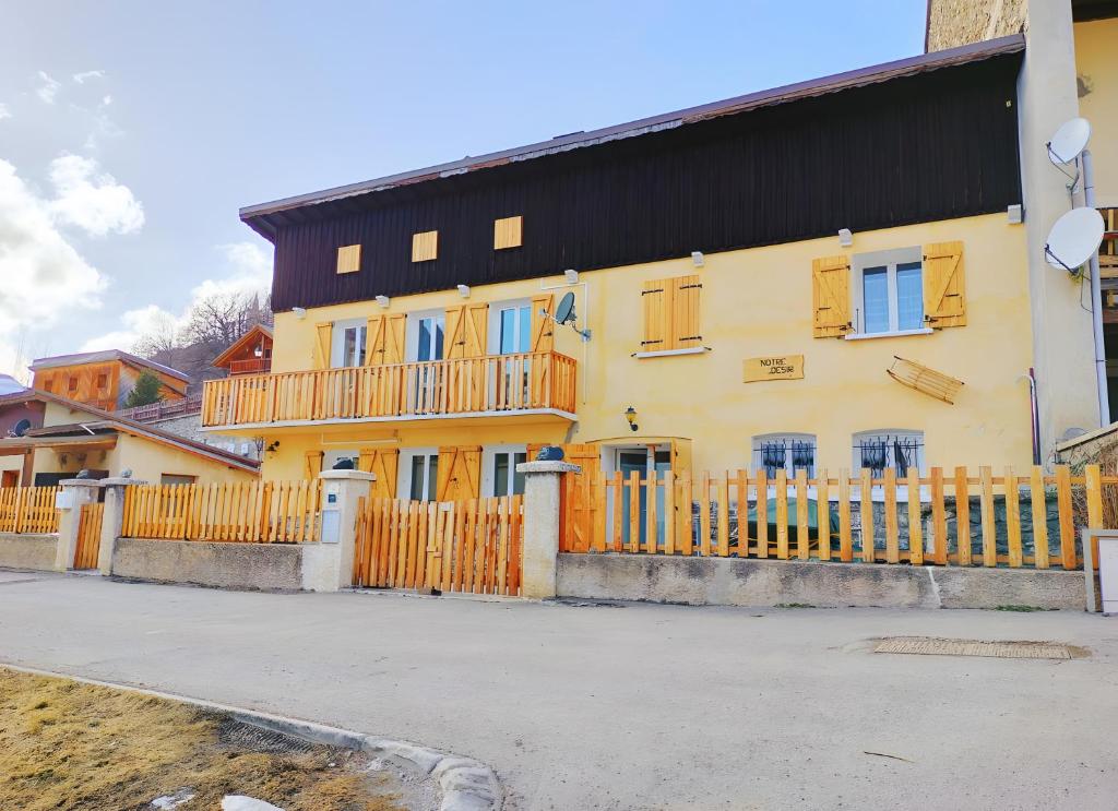 a yellow house with a black roof and a fence at Gite Notre Désir in Abriès