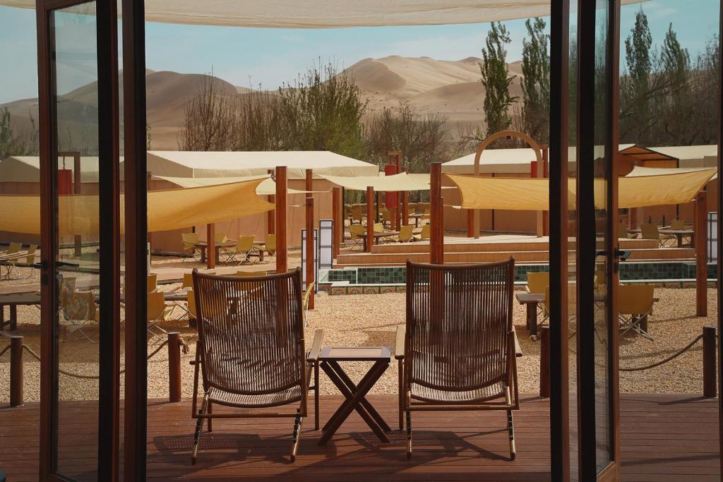 two chairs and tables and umbrellas on a patio at DunHuang FengMingSha Hotel in Dunhuang