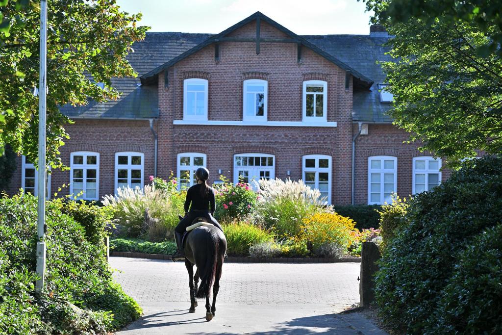 a woman riding a horse in front of a house at Familienfreundliche Ferienwohnungen auf idyllischer Reitanlage - Hof Norwegen in Mohrkirch