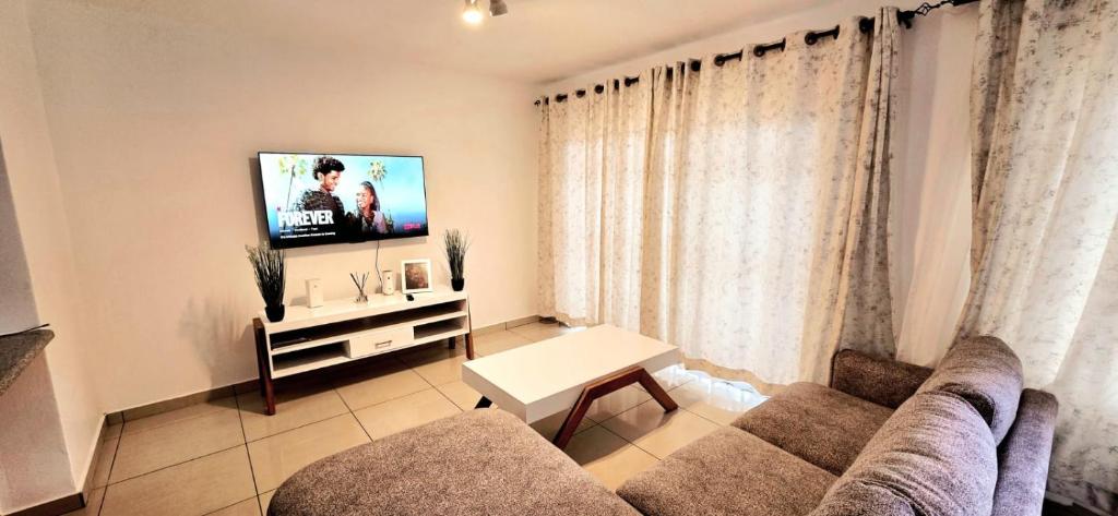ein Wohnzimmer mit Couch und Flachbildfernseher in der Unterkunft 3 Bedroom Apartment in Roodepoort