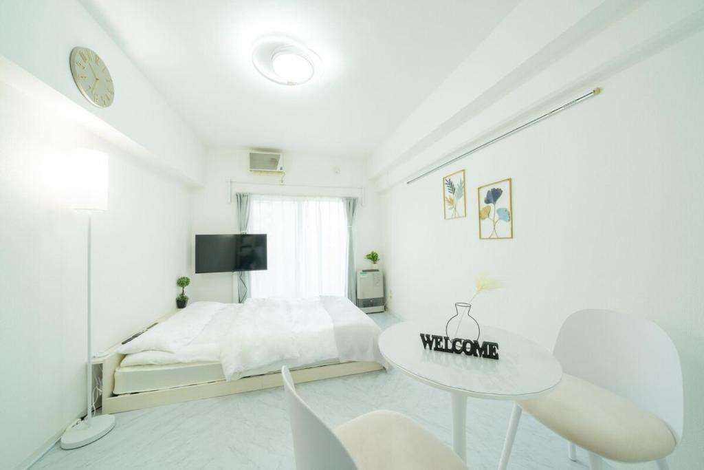 een witte slaapkamer met een bed en een tafel bij Maison de Grue 601 in Sapporo