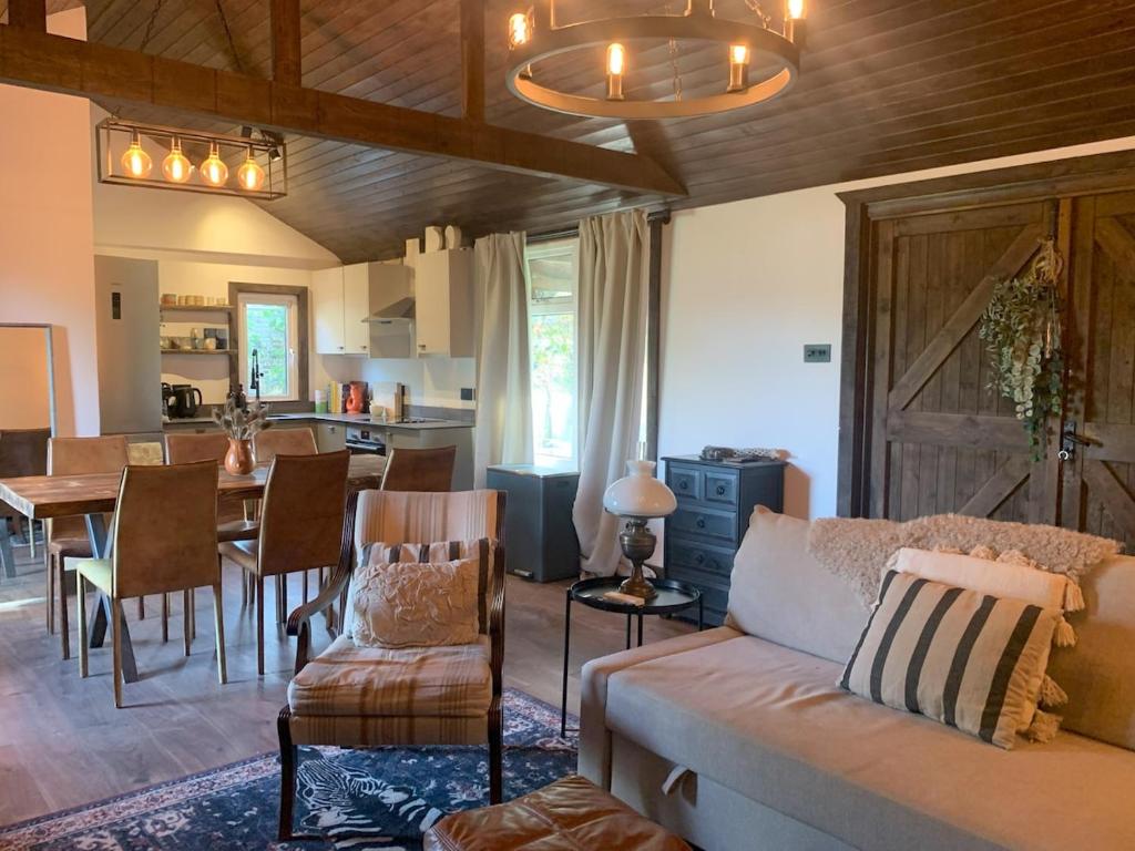a living room with a couch and a dining room at Hunters Cabin - Rustic farm stay in Great Chart