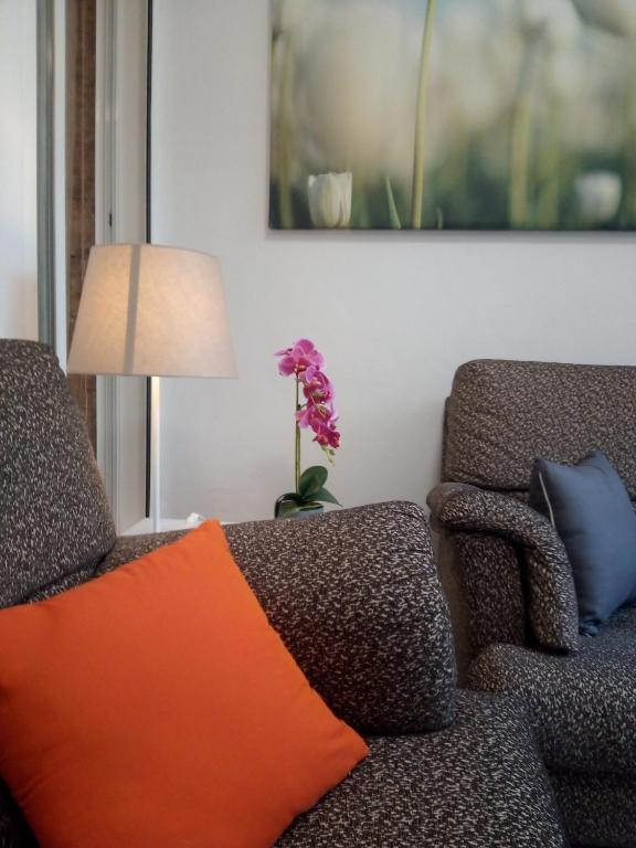 a couch with an orange pillow next to a lamp at Espai One Valencia in Valencia