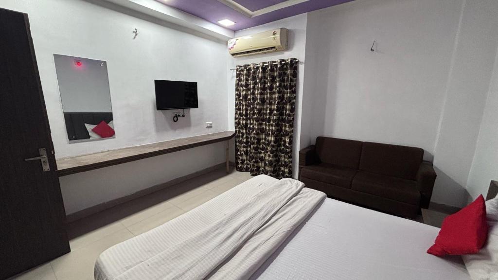 Un dormitorio con una cama, un sofá y un televisor. en Hotel O Green Park, en Ambaji