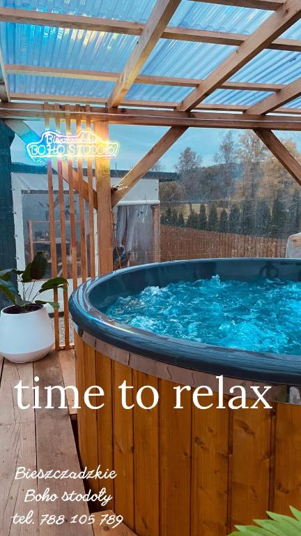a hot tub on a deck with a pergola at Bieszczadzkie BOHO stodoły z jacuzzi i sauna na wyłączność in Myczkowce