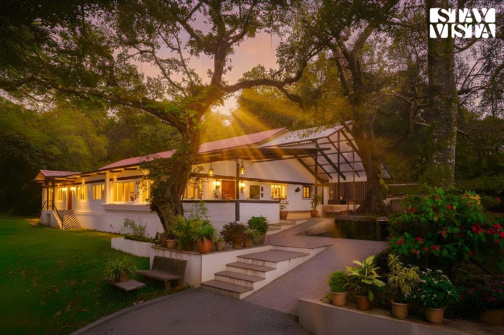une maison avec un arbre dans la cour dans l'établissement StayVista at The Floramer with Bonfire, Lawn, à Panchgani
