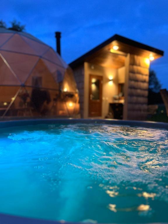 a swimming pool in front of a house at night at River Camp in Lembuži