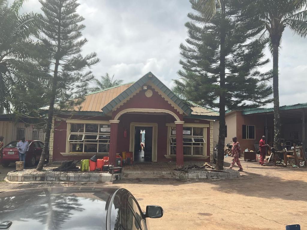 a red house with people standing outside of it at Otam homes in Akure