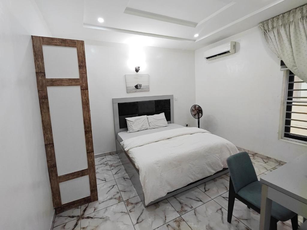 a white bedroom with a bed and a mirror at Abuja Shortlet City with 24hr power, Wifi, Fully Secured Environment in Abuja