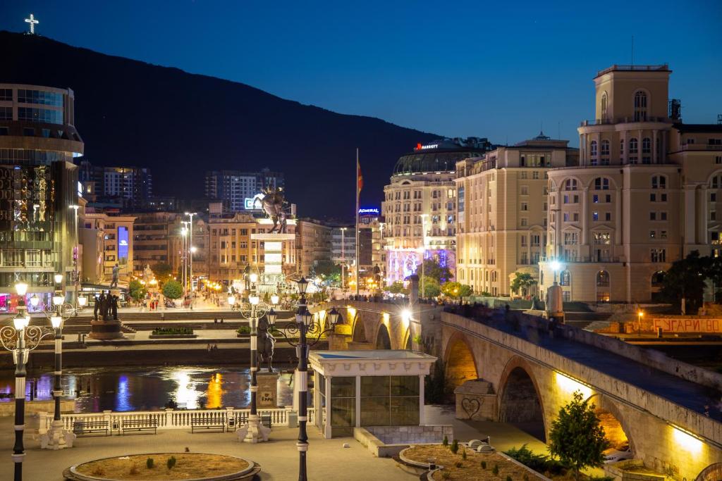 a city at night with a bridge and buildings at Central Saga Apartment in Skopje