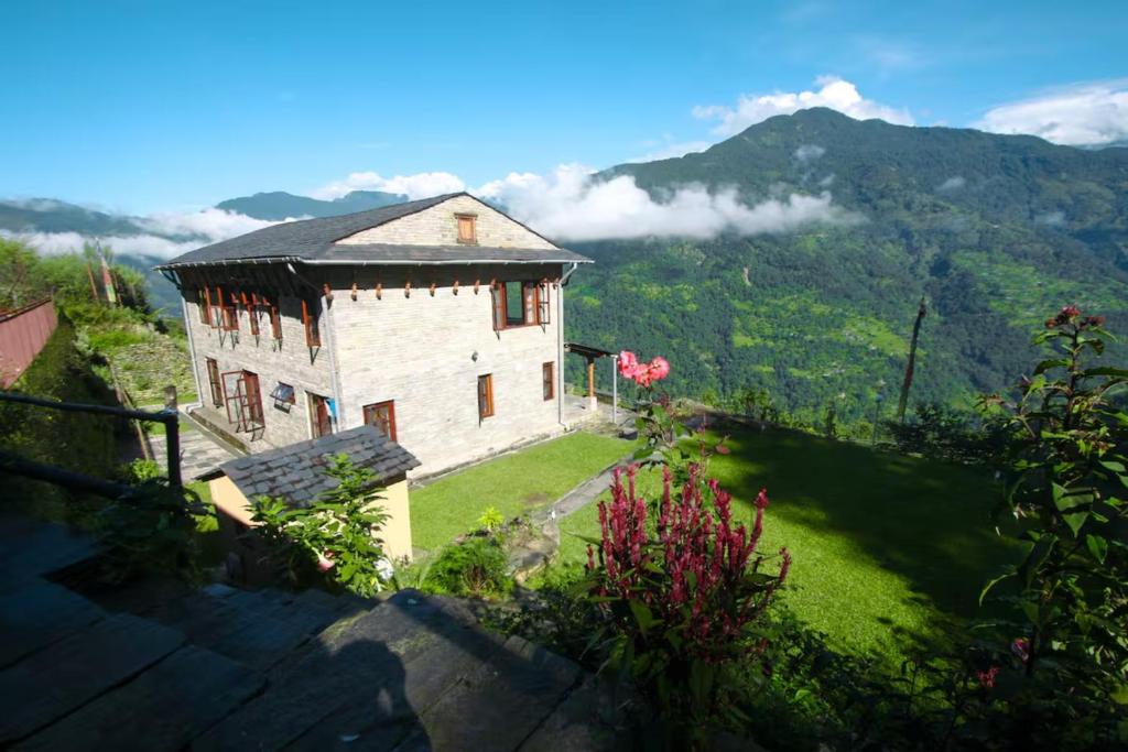 a house on a hill with mountains in the background at Mahakaruna mountain villa, peaceful family retreat with Himalayan views and Private Cook in Pokhara