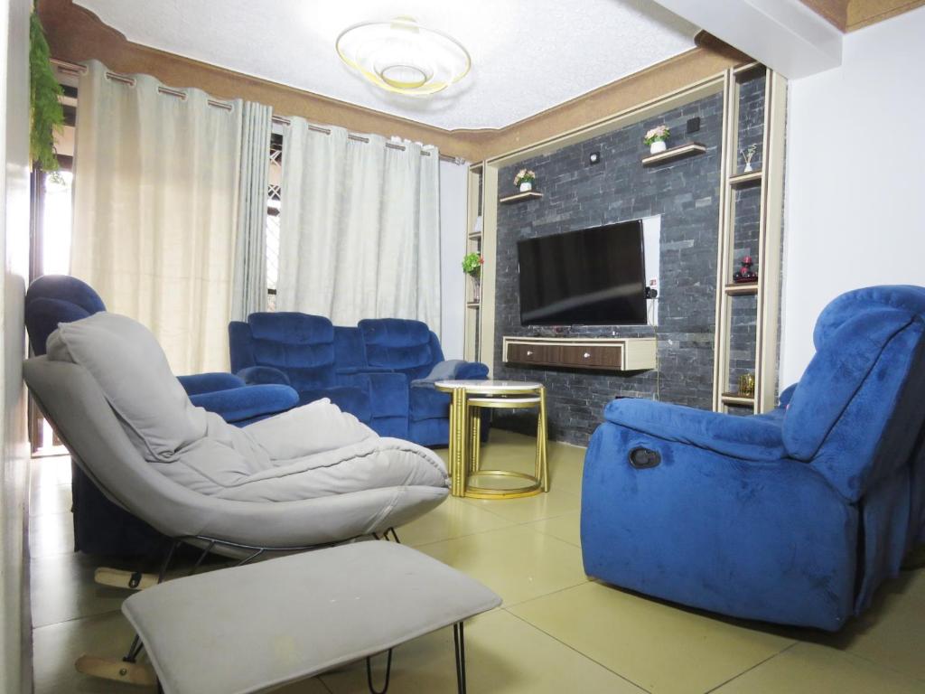a living room with blue chairs and a tv at AG Home in Kampala