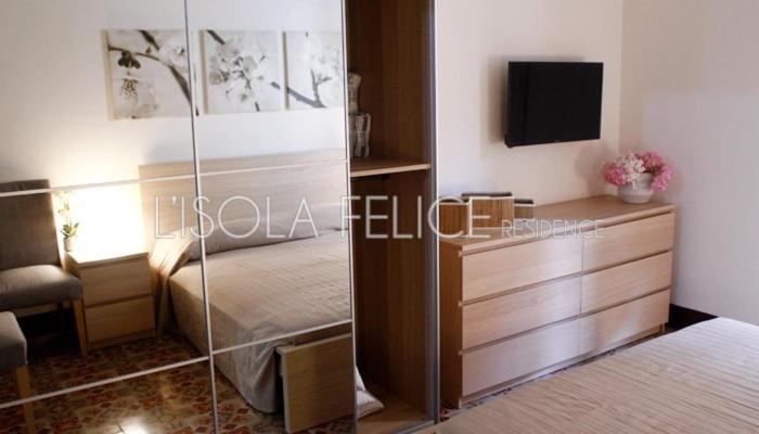 a bedroom with a bed and a dresser with a television at isola felice residence - Family Apartment in Trapani