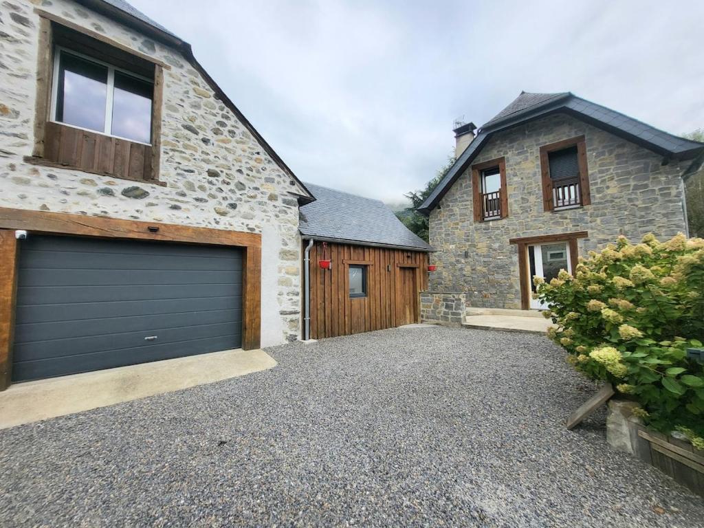 a house with a garage door and a building at Maison des Cimes, Garden, cozy for 8 people in Ayzac-Ost