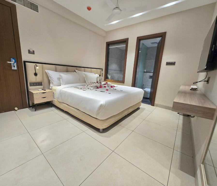 a bedroom with a large white bed and a television at Aarambh By The Sky Imperial Indore in Indore