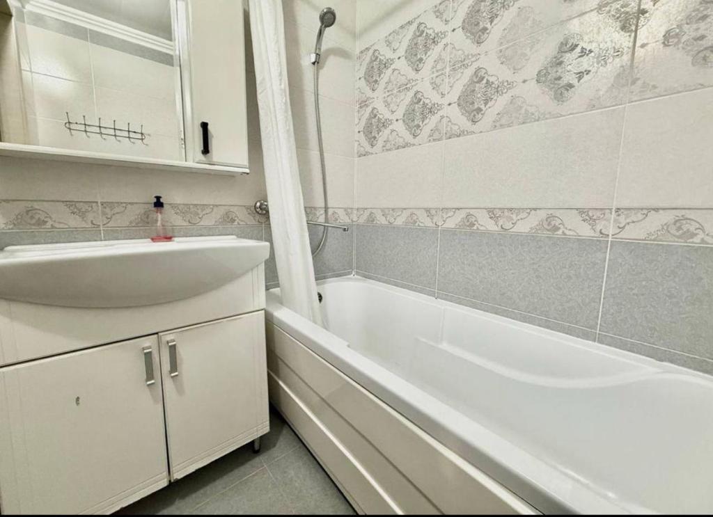 a white bathroom with a sink and a bath tub at Buiucani in Chişinău