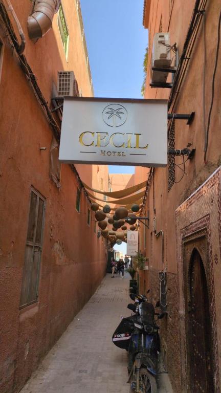a sign for an old house with a motorcycle parked on a alley at Hotel Cecil in Marrakech