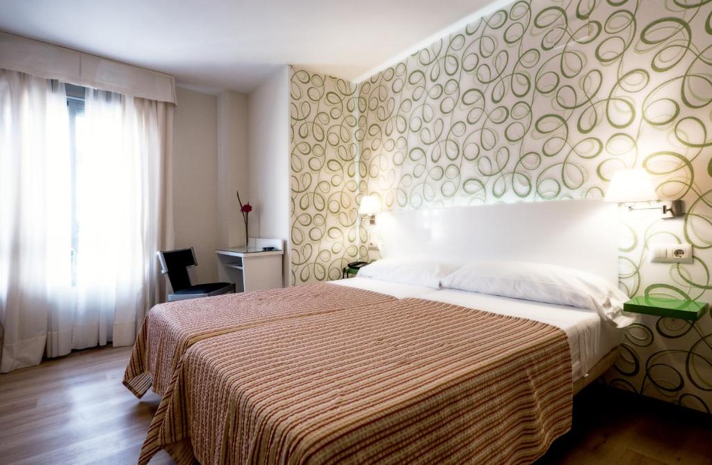 1 dormitorio con 1 cama grande con colcha marrón y blanco en Hotel Plaza Santa Lucía, en Sevilla