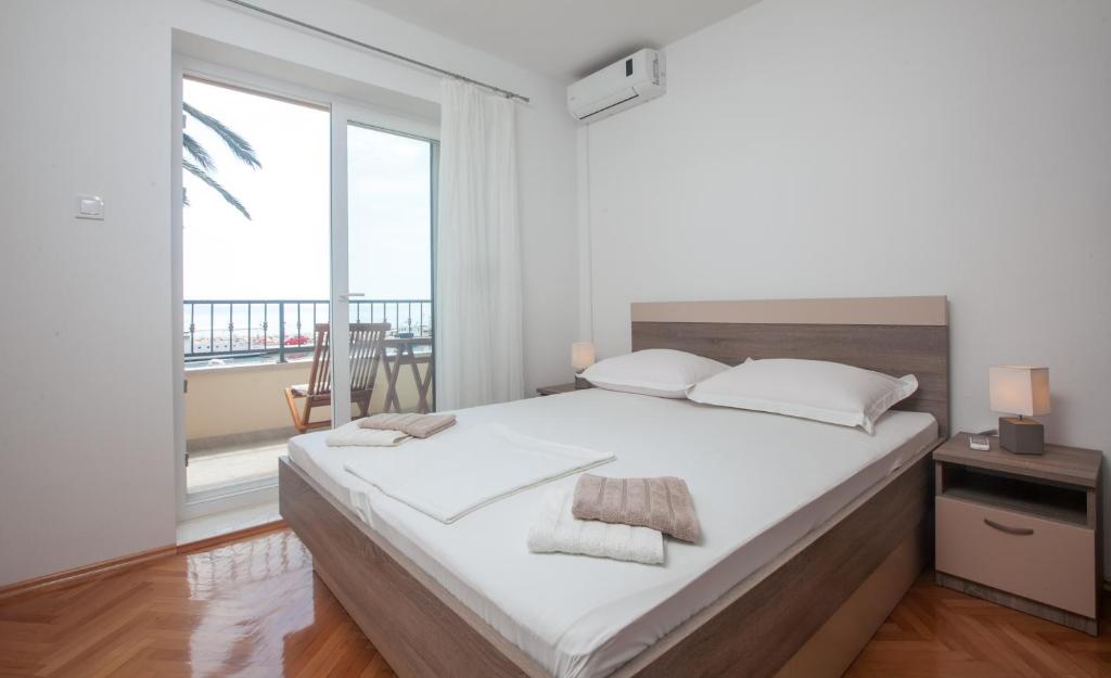 a bedroom with a large bed and a large window at Apartments Gaston in Podgora