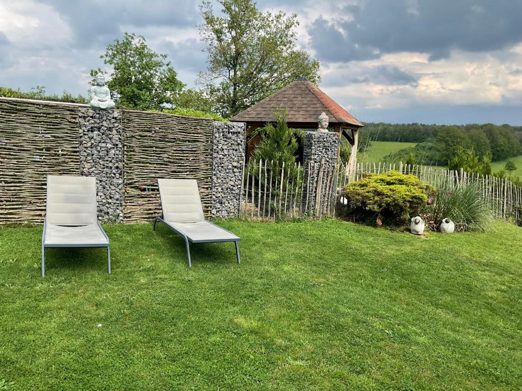 two chairs sitting in the grass near a fence at La Belle vue in Durbuy