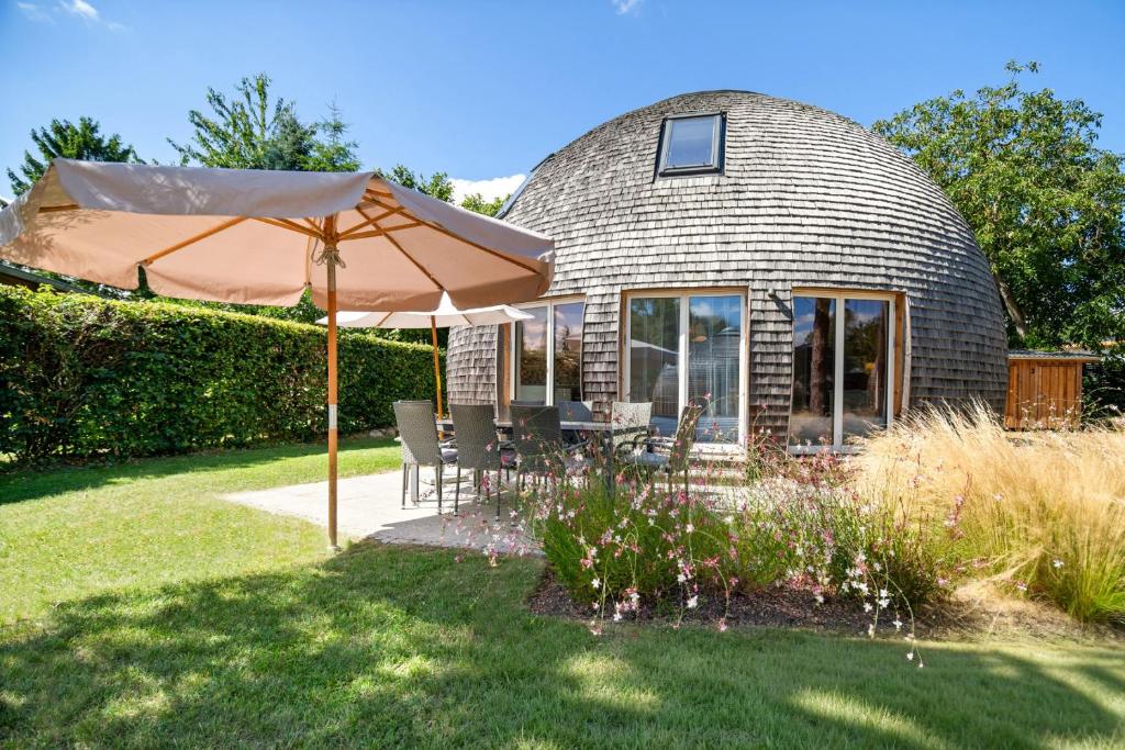 a house with an umbrella in the yard at Kugelhaus Solveig - Zeitloses Holzhaus in Kugelform für stille Momente in der Natur in Wustrow