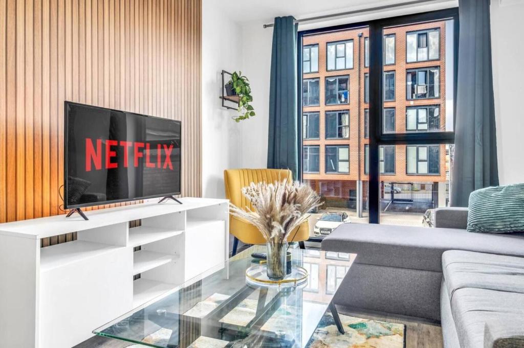 a living room with a tv on a white entertainment center at Charming Deritend Apartment with Full Access for Wheelchairs in Birmingham