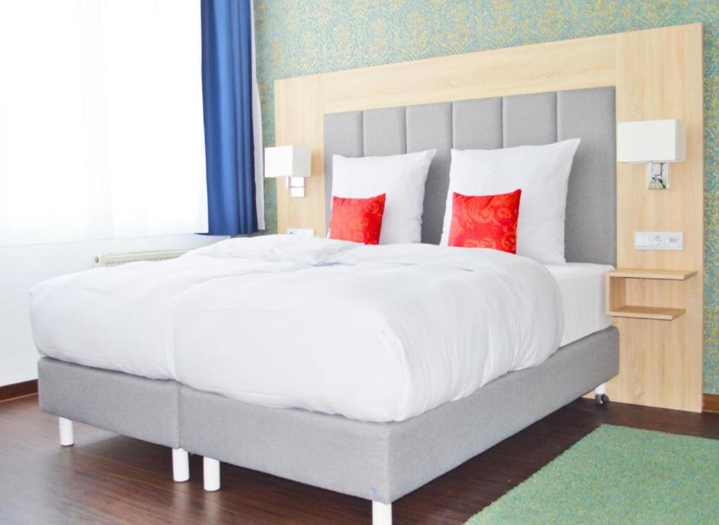 a bedroom with a large bed with red pillows at Pallas Hotels in Darmstadt