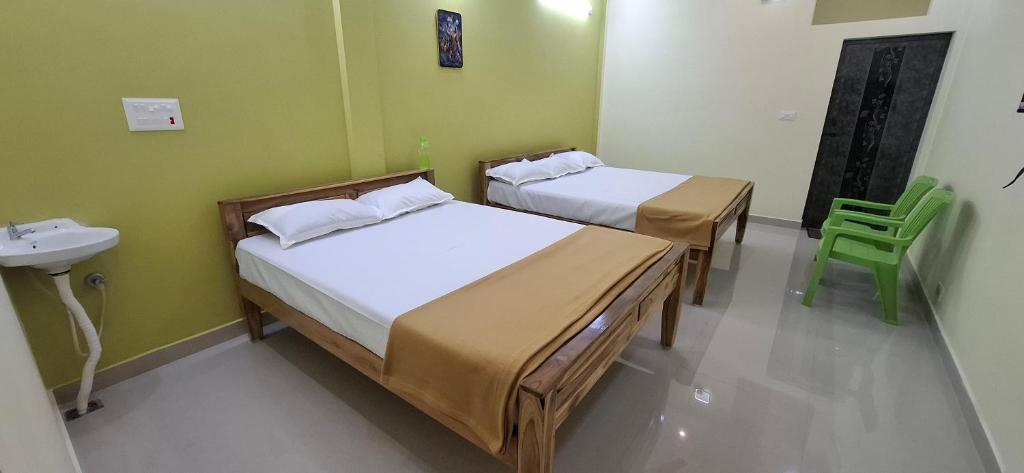 two beds in a room with a sink and a sink at A J Home Stay in Tiruvannāmalai