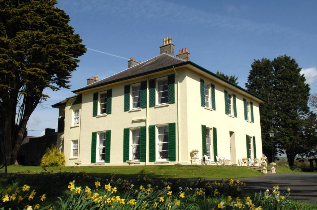 una gran casa blanca con persianas verdes en Elm Grove Country House, en Tenby