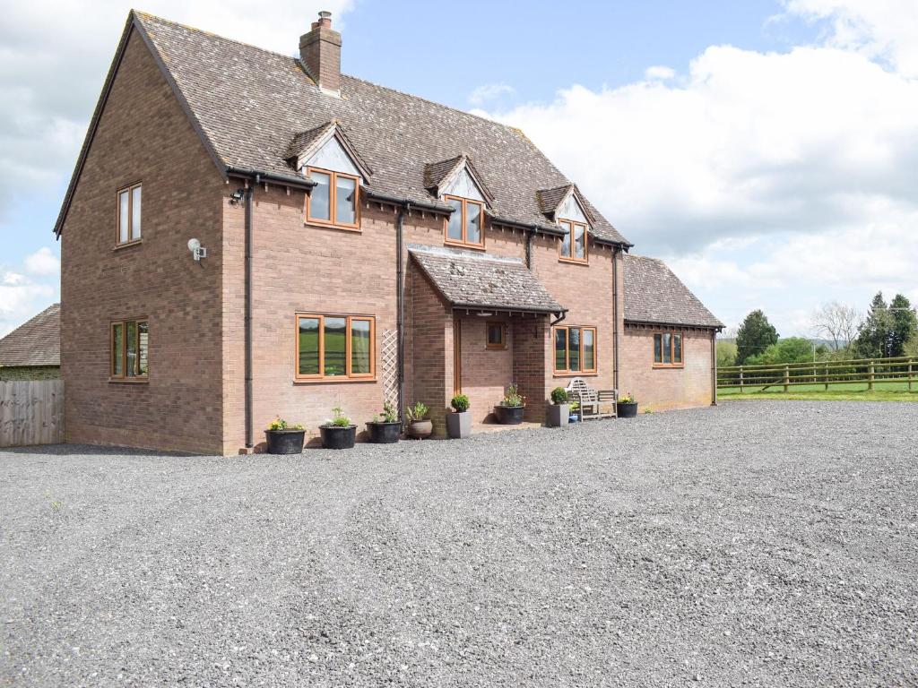 a large brick house with potted plants on the driveway at The Larches in Hopton Cangeford